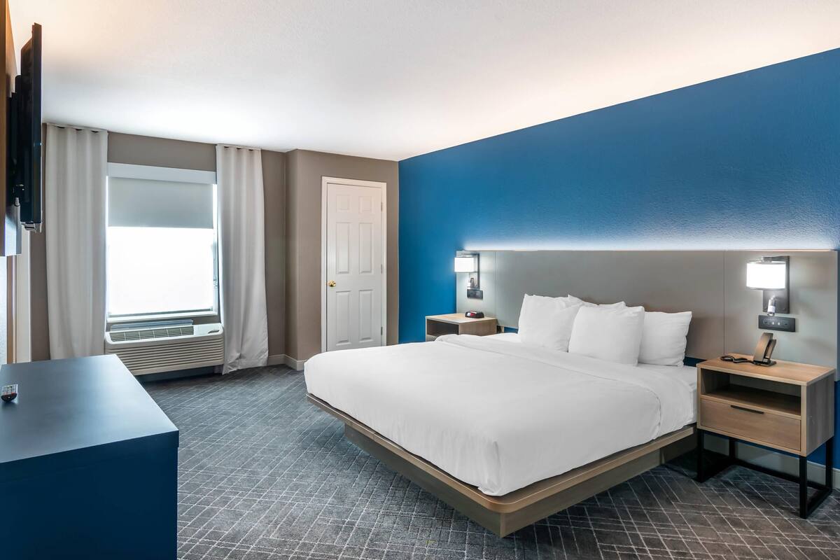 A hotel room with a bed, bedside tables, a desk, and a TV.