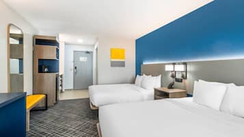 Habitació d'hotel amb dos llits, un escriptori, un mirall i un armari.