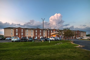 A hotel with a brick facade, multiple parking spaces, and a grassy area in the foreground. - Comfort Inn & Suites Chesterfield - St. Louis (Chesterfield)