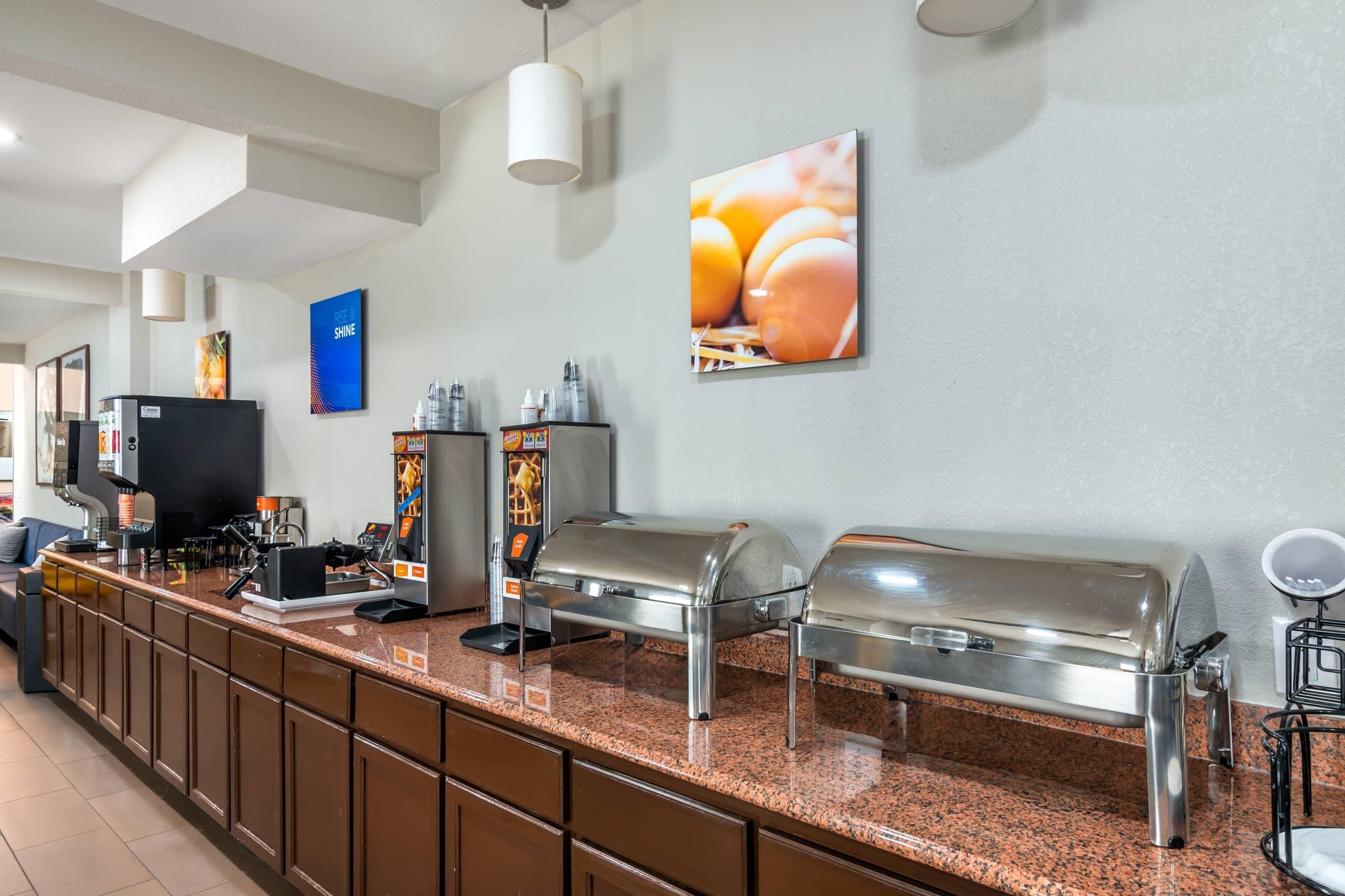 Mostrador de buffet con electrodomésticos de acero inoxidable, una máquina de café y un letrero en la pared.