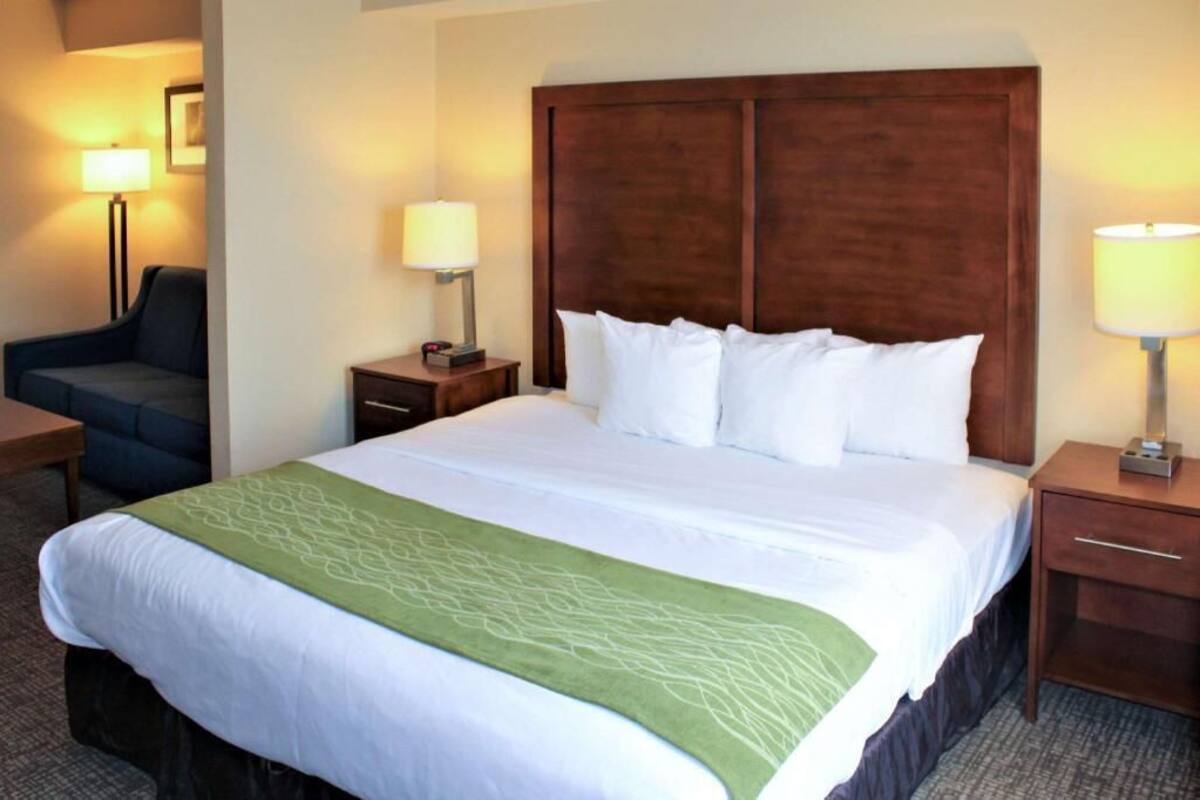 A hotel room with a large bed, two bedside tables, a nightstand, a chair, and two lamps.
