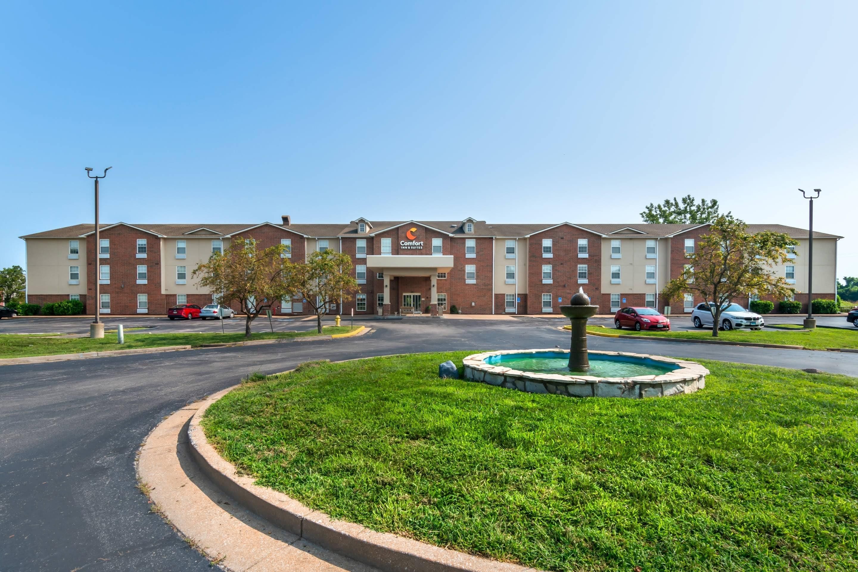 A hotel with a central courtyard, a fountain, and a parking lot.