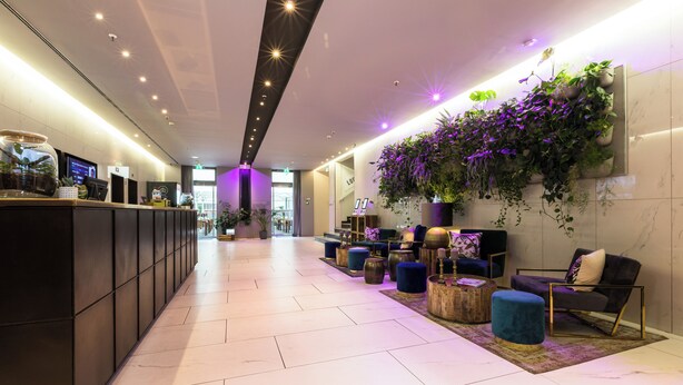 A modern lobby with a reception desk, seating area, and a wall-mounted plant display. - Lindner Hotel Berlin Ku’damm, part of JdV by Hyatt (Berlin)