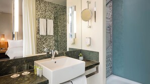 A modern bathroom with a large white sink, a glass shower enclosure, and a mirror with a round frame. - Lindner Hotel Berlin Ku’damm, part of JdV by Hyatt (Berlin)