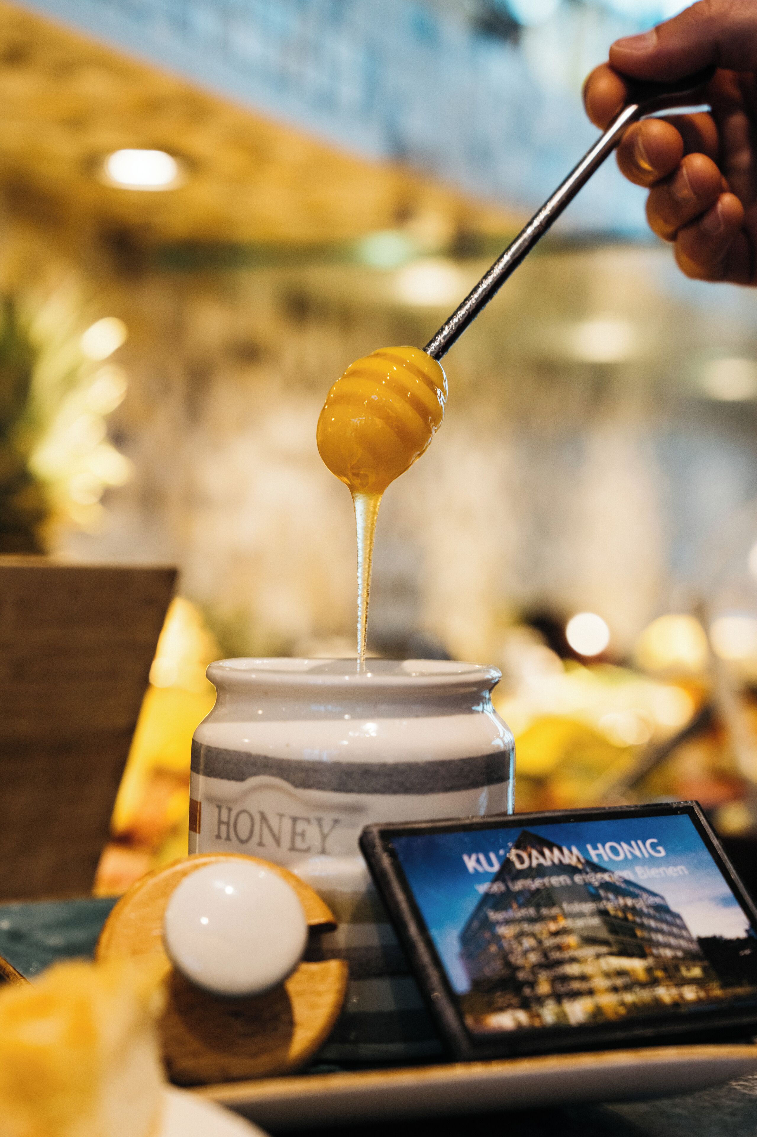 A honey jar with a spoonful of honey being lifted.