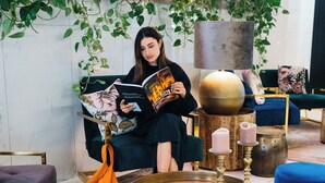 A cozy reading nook with a person reading a book, surrounded by plush seating and a decorative wall with greenery. - Lindner Hotel Berlin Ku’damm, part of JdV by Hyatt (Berlin)