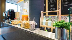 A breakfast bar with various food items and a coffee machine. - Lindner Hotel Berlin Ku’damm, part of JdV by Hyatt (Berlin)