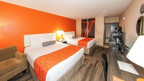 Een hotelkamer met twee bedden, een bank, een bureau en een kitchenette.