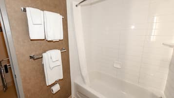 A bathroom with a bathtub, white tiles, and two towels hanging on a rack.