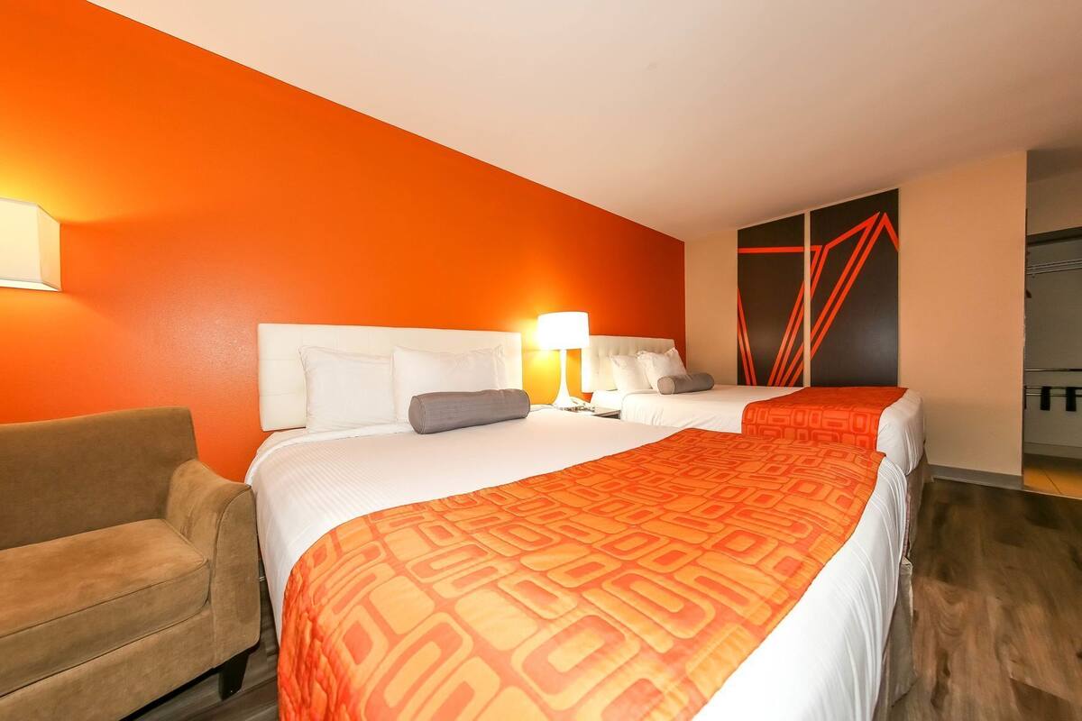 Quarto de hotel com duas camas, um sofá e design moderno.