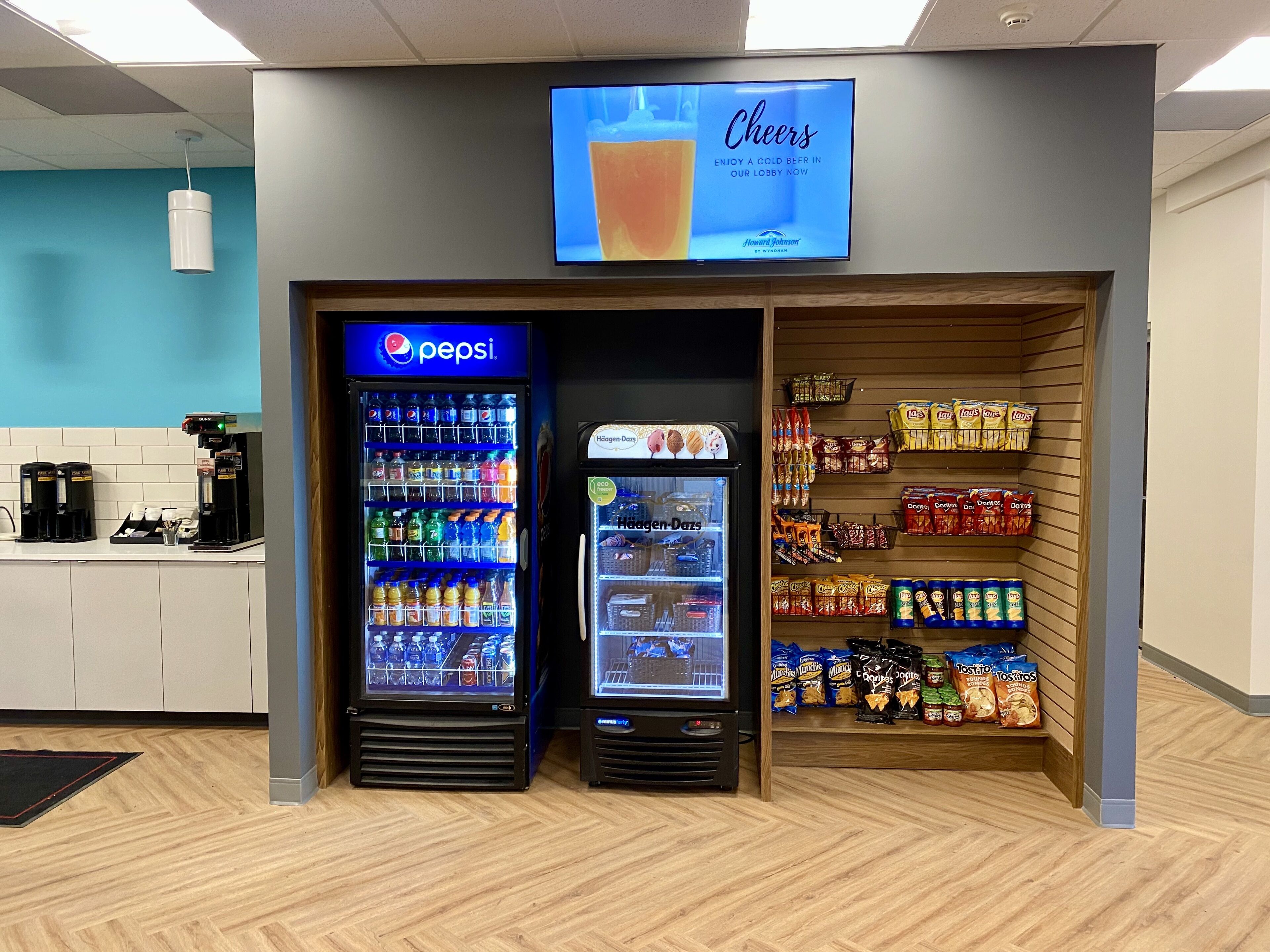 Un espace comprenant un distributeur automatique de boissons, avec des produits Pepsi et un présentoir réfrigéré, le tout entouré d’étagères remplies d’en-cas.