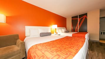 Ett hotellrum med två sängar, en soffa och en knallorange vägg.