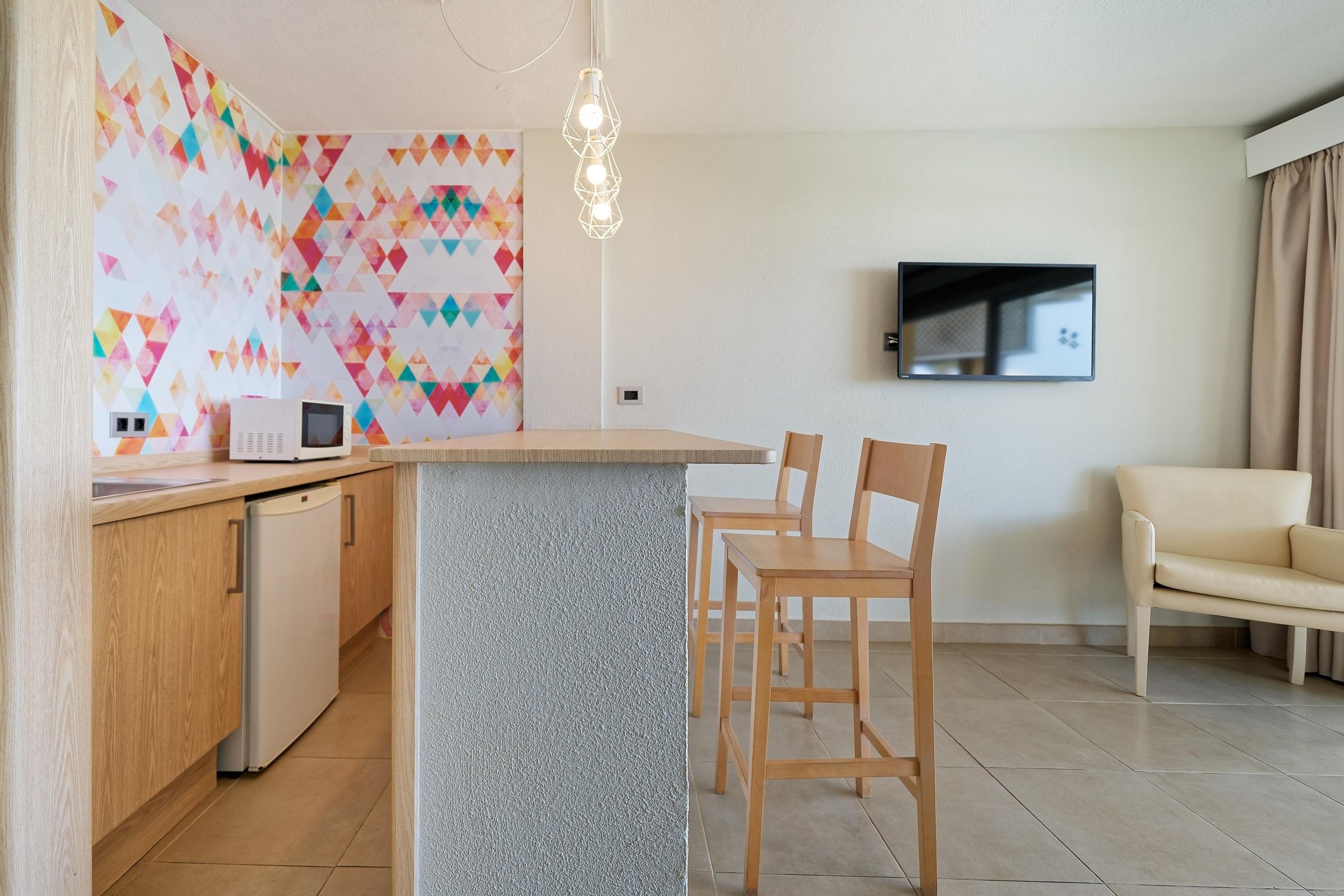 Eine moderne Küche mit integrierter Kochinsel, Holzkohle, einer Couch und einem an der Wand befestigten Flachbildfernseher.