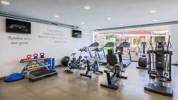 Un gimnasio con cintas de correr, bicicletas estáticas y pesas rusas.