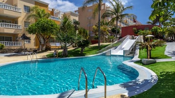 A swimming pool with a curved edge, surrounded by a well-maintained lawn and palm trees.