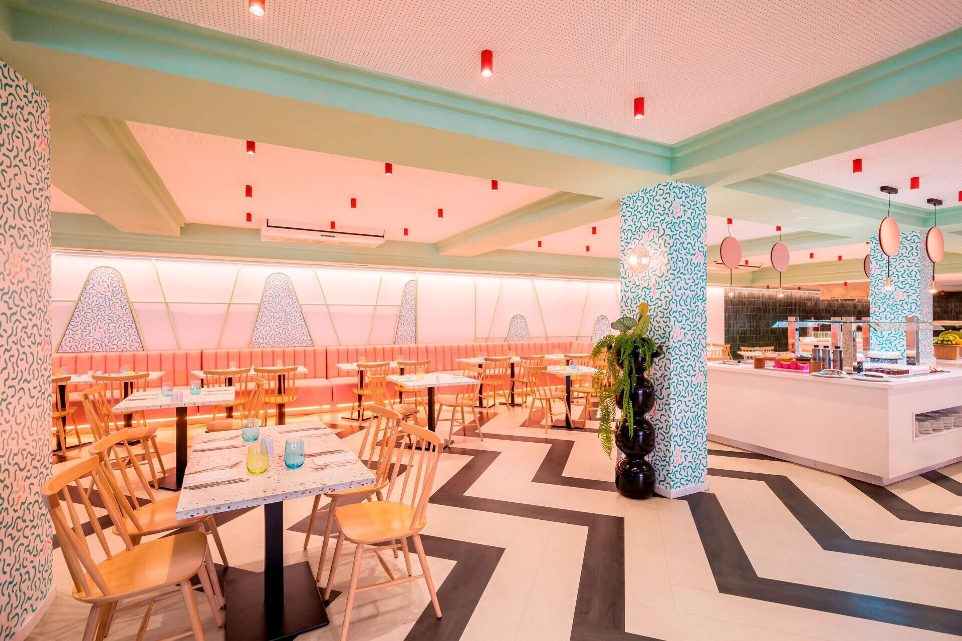 Un interior de restaurante moderno con cabinas y mesas, un pilar con diseño y una zona de barra.