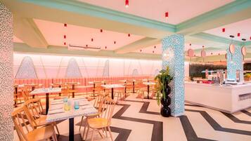 Un interior de restaurante moderno con cabinas y mesas, un pilar con diseño y una zona de barra.