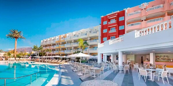 Un hôtel doté d’une piscine, d’un espace extérieur aménagé et dont le bâtiment est de couleur rouge.