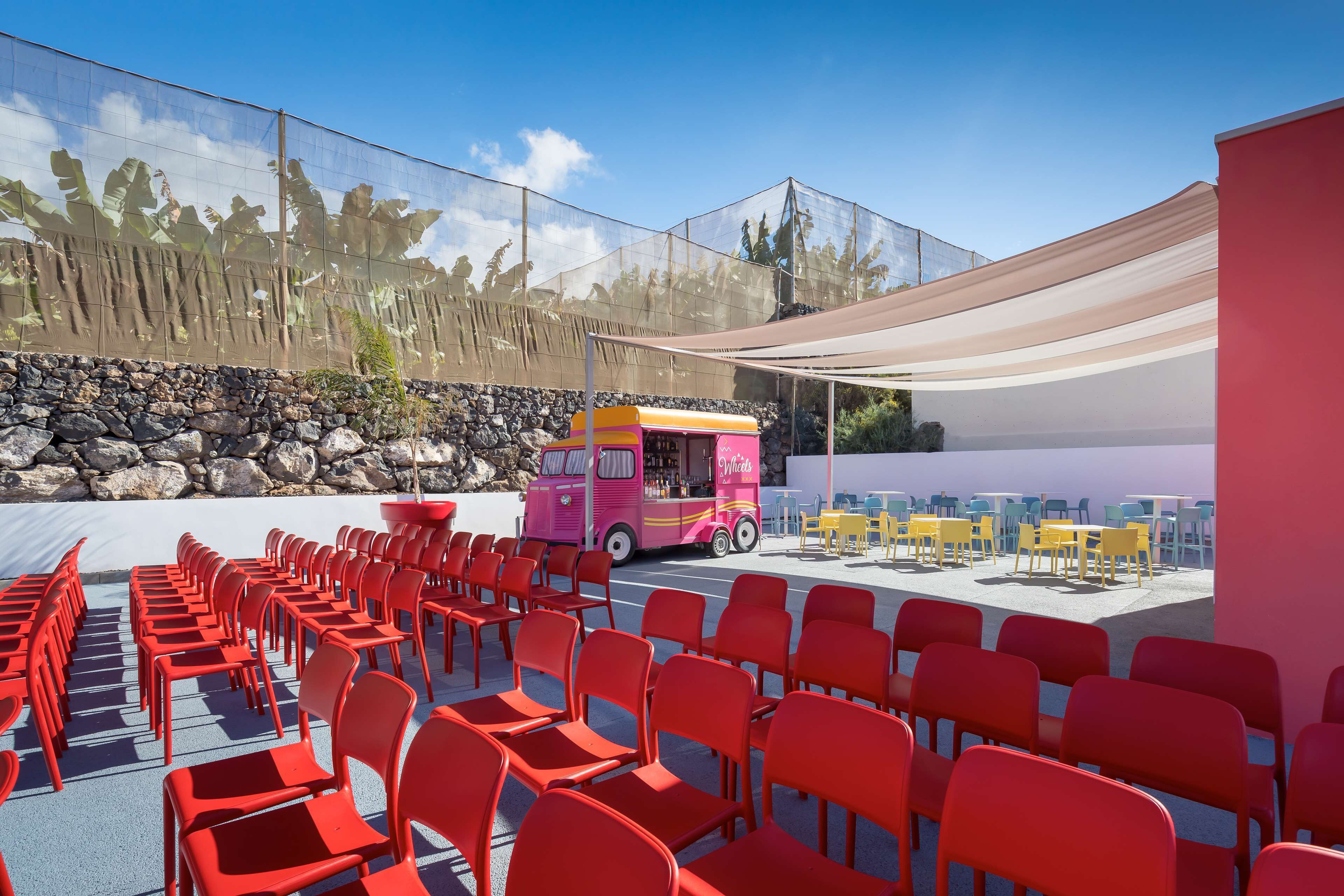 A seating area with red chairs and a pink food truck.