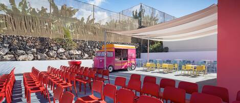 A seating area with red chairs and a pink food truck.
