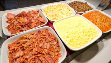 Un bufé con diferentes opciones de comida, incluyendo tocino, huevos y frijoles.