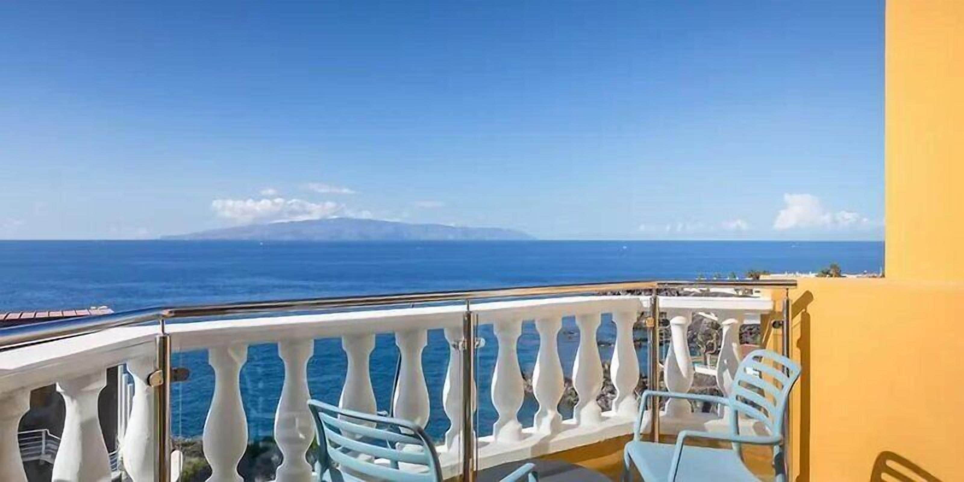 Un balcon avec vue sur la mer et sur une montagne lointaine.