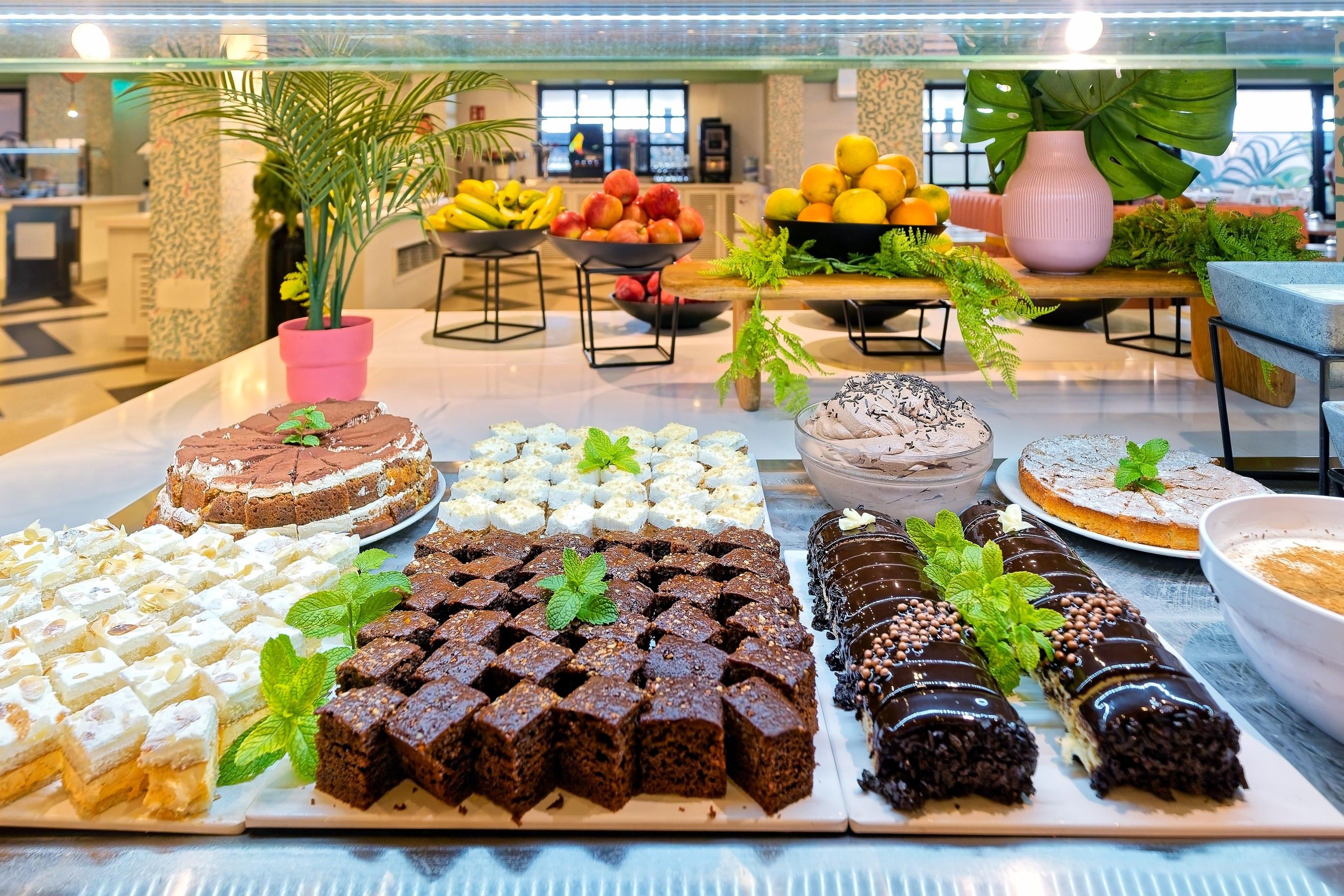 Un bufé con diversos postres, incluyendo pasteles, brownies y repostería.