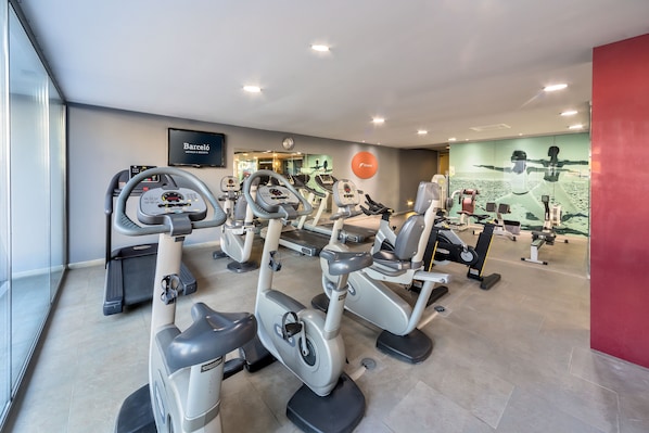 Un gimnasio con bicicletas estáticas, cintas de correr y demás equipamiento de fitness.