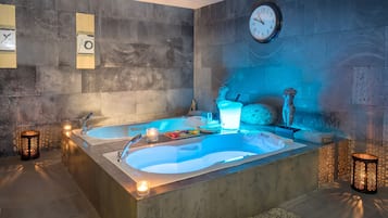 Un baño moderno con dos tinas grandes, un reloj y apliques decorativos.
