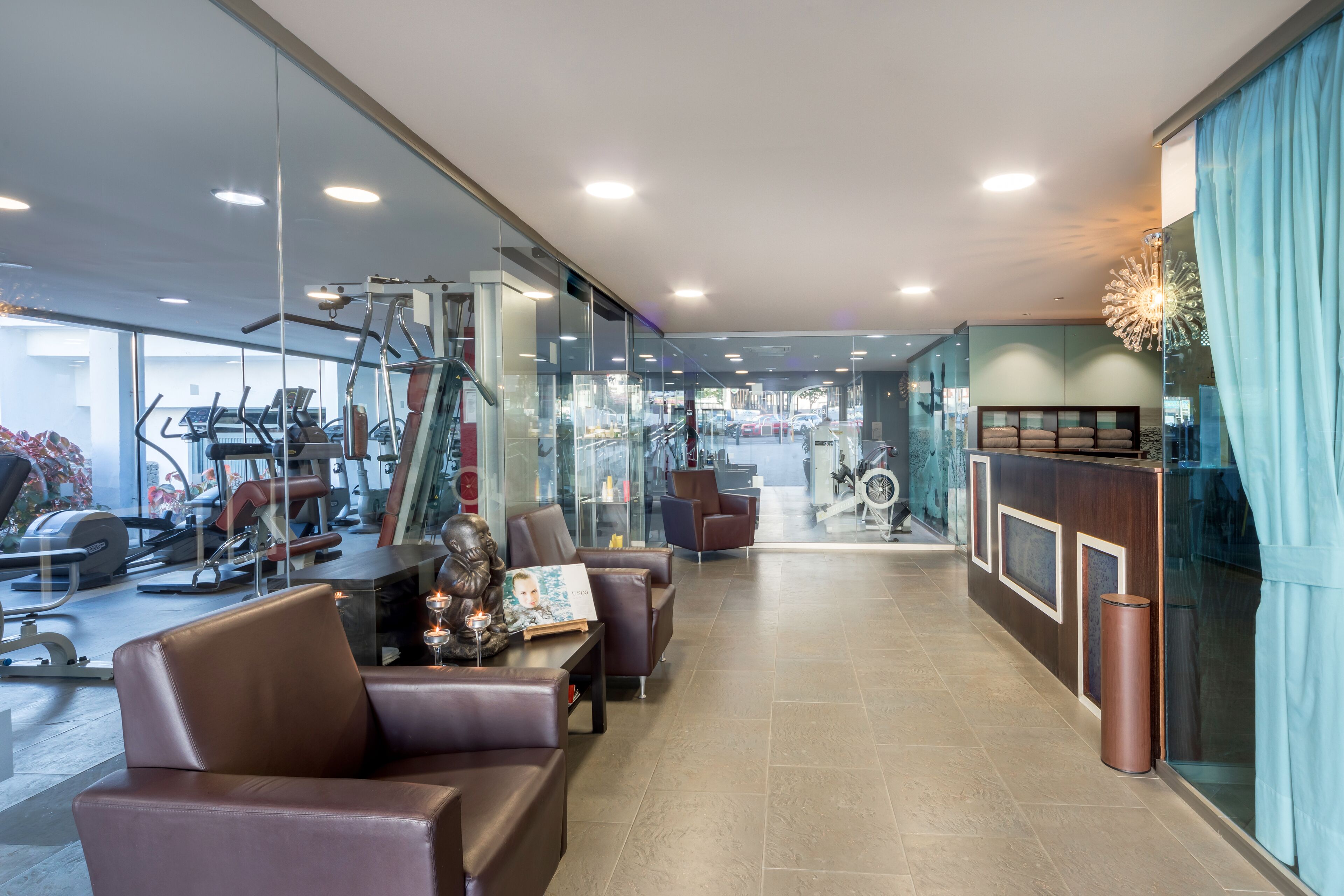A modern hotel lobby with a fitness center, leather seating, and a reception desk.