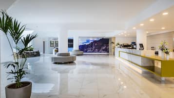 Un moderno vestíbulo de hotel con piso de mármol, una mesa de recepción y un mural grande en la pared.