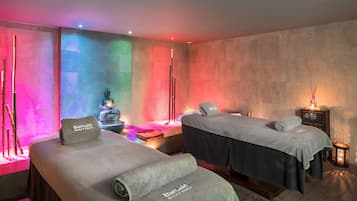 Un cuarto de spa con dos camillas de masaje, una pequeña fuente e iluminación ambiental.