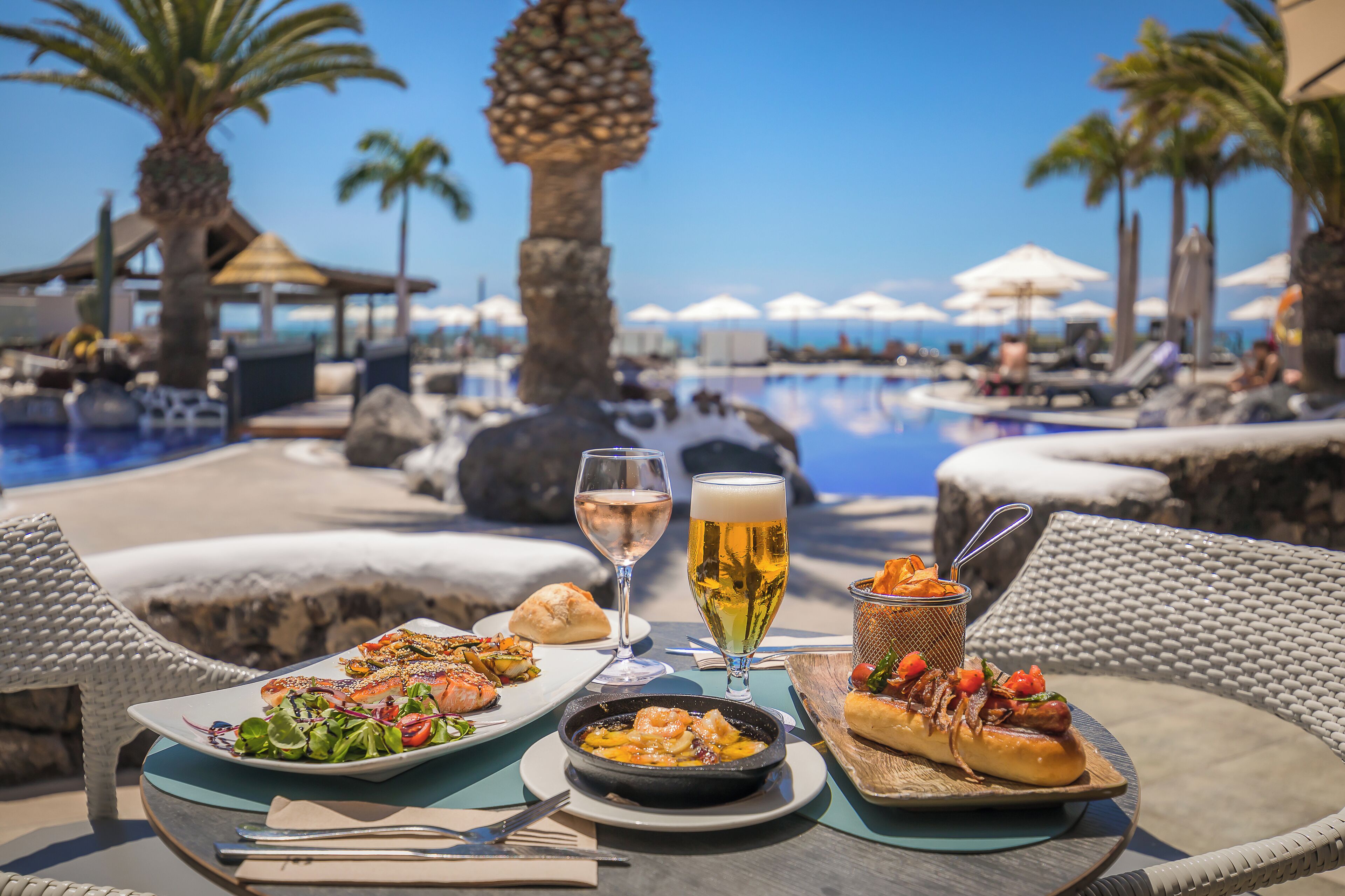 Ein Esstisch mit Meeresfrüchten, einem Bierglas und einer Schüssel Chips an einem Pool.