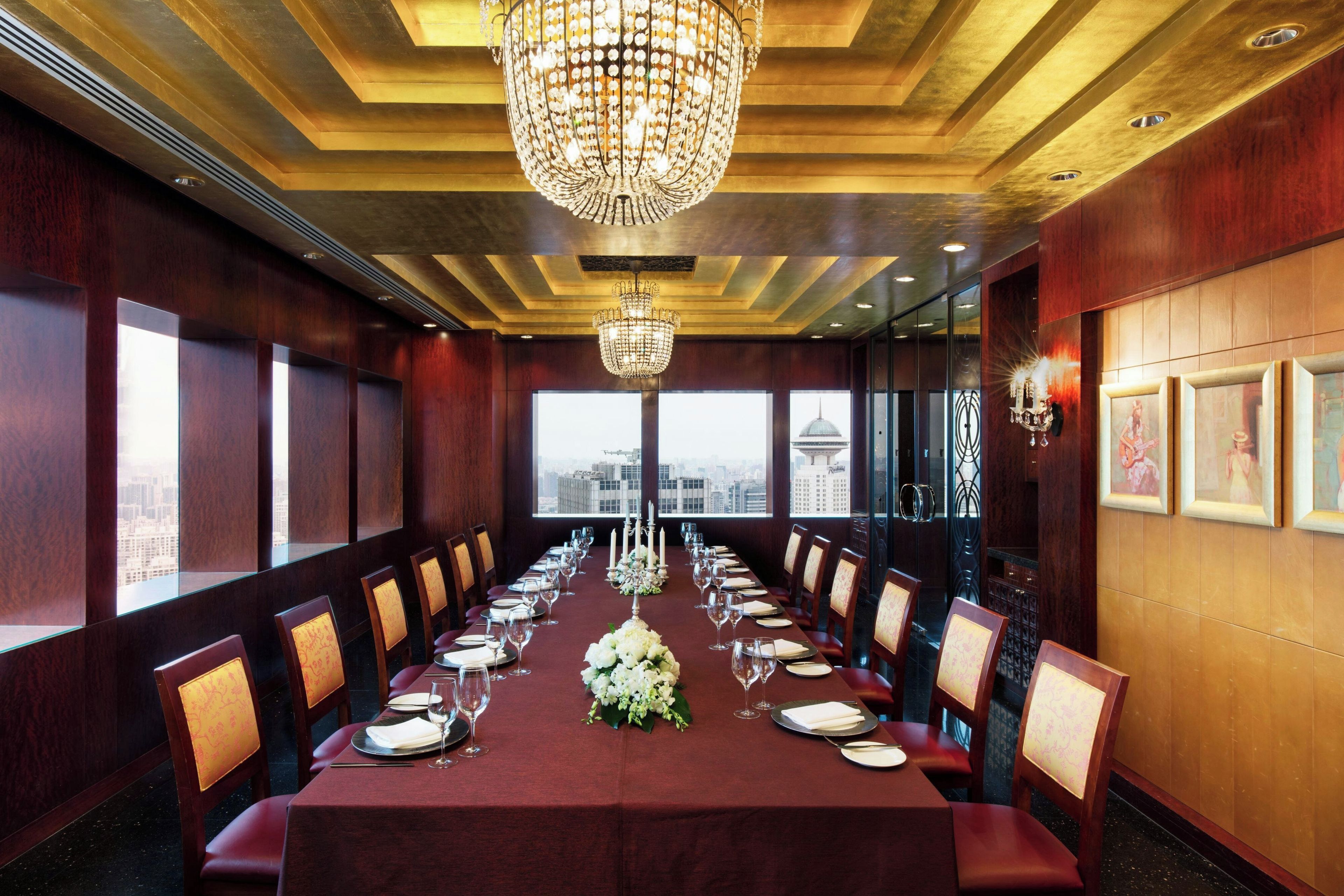 A conference room with a long table set for a meeting, large windows, and a chandelier.