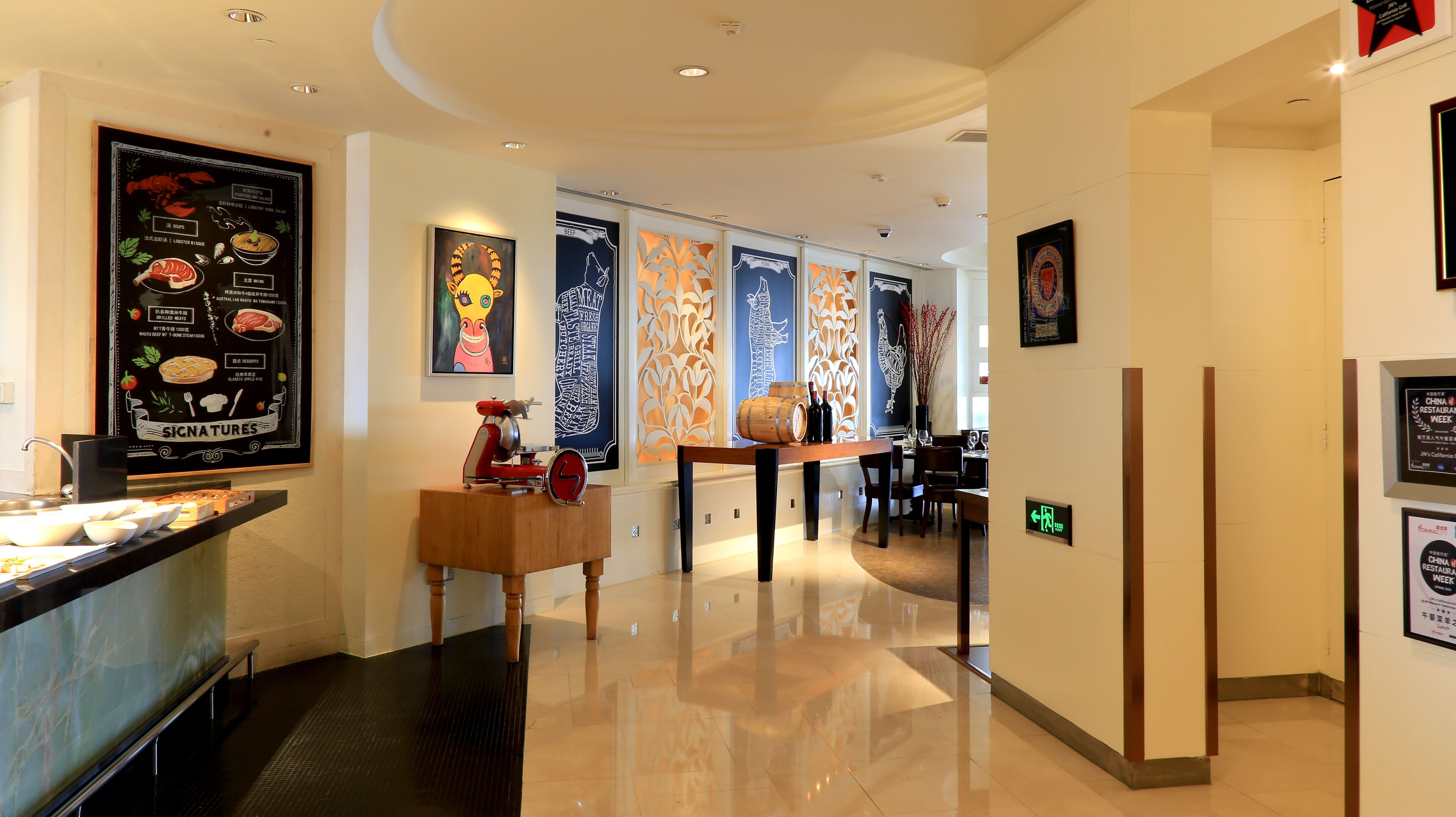 Un hall d’hôtel moderne comprenant un comptoir d’accueil, un espace repas et un mur orné de tableaux.