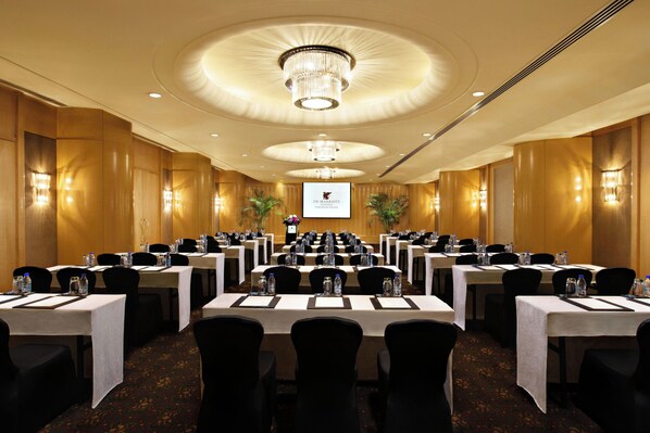 A conference room with multiple tables, chairs, and a large screen at the front. - JW Marriott Hotel Shanghai Tomorrow Square (Shanghai)