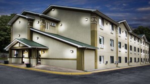 A multi-story hotel with a green roof, a covered entrance, and multiple air conditioning units.