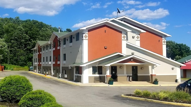 A multi-story hotel with a red and white facade, a covered entrance, and a parking lot.