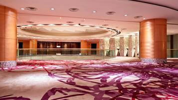 A spacious lobby with a high ceiling, marble columns, and a patterned carpet.