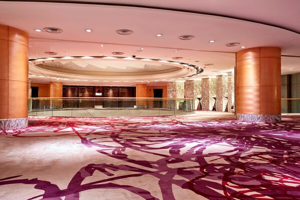 Un amplio vestíbulo con techo alto, columnas de mármol y alfombra estampada.