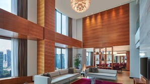 A spacious living area with a large window, a red carpet, and a modern chandelier.