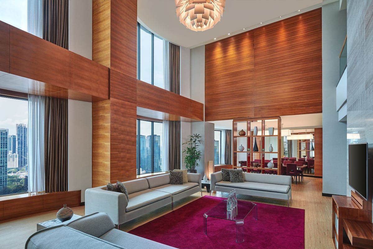 A spacious living area with a large window, a red carpet, and a modern chandelier.