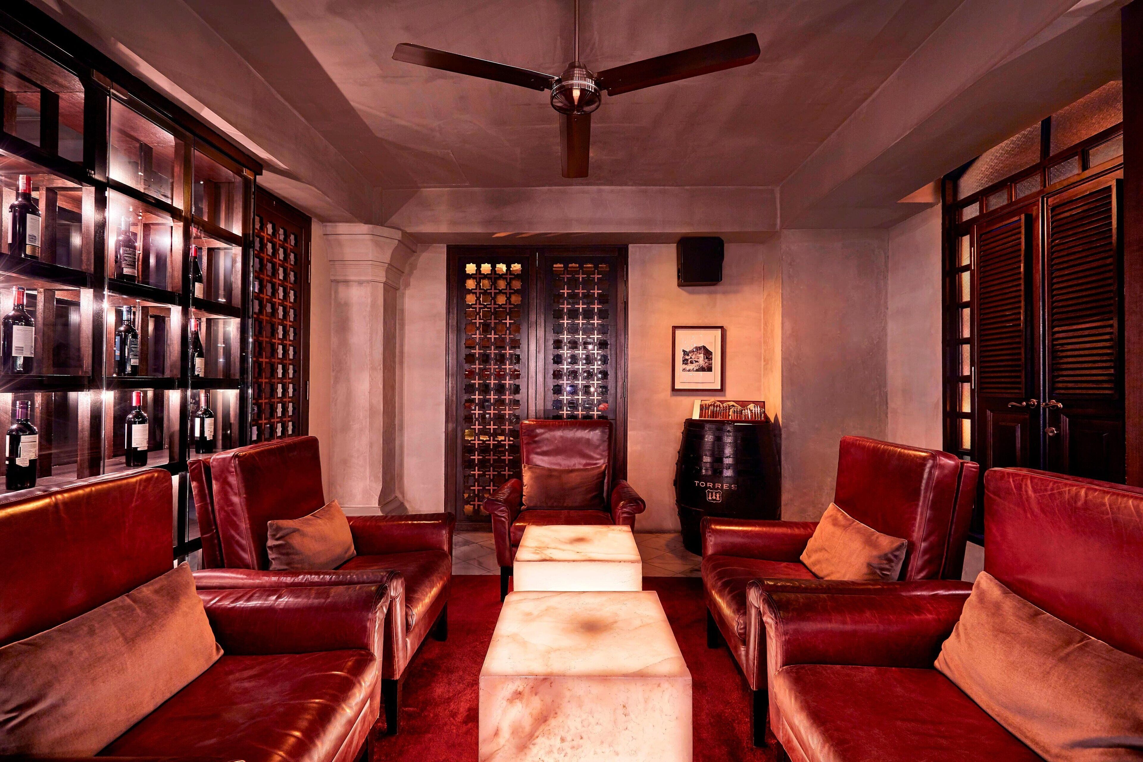 A room with leather sofas, a central coffee table, a wine rack, and a ceiling fan.