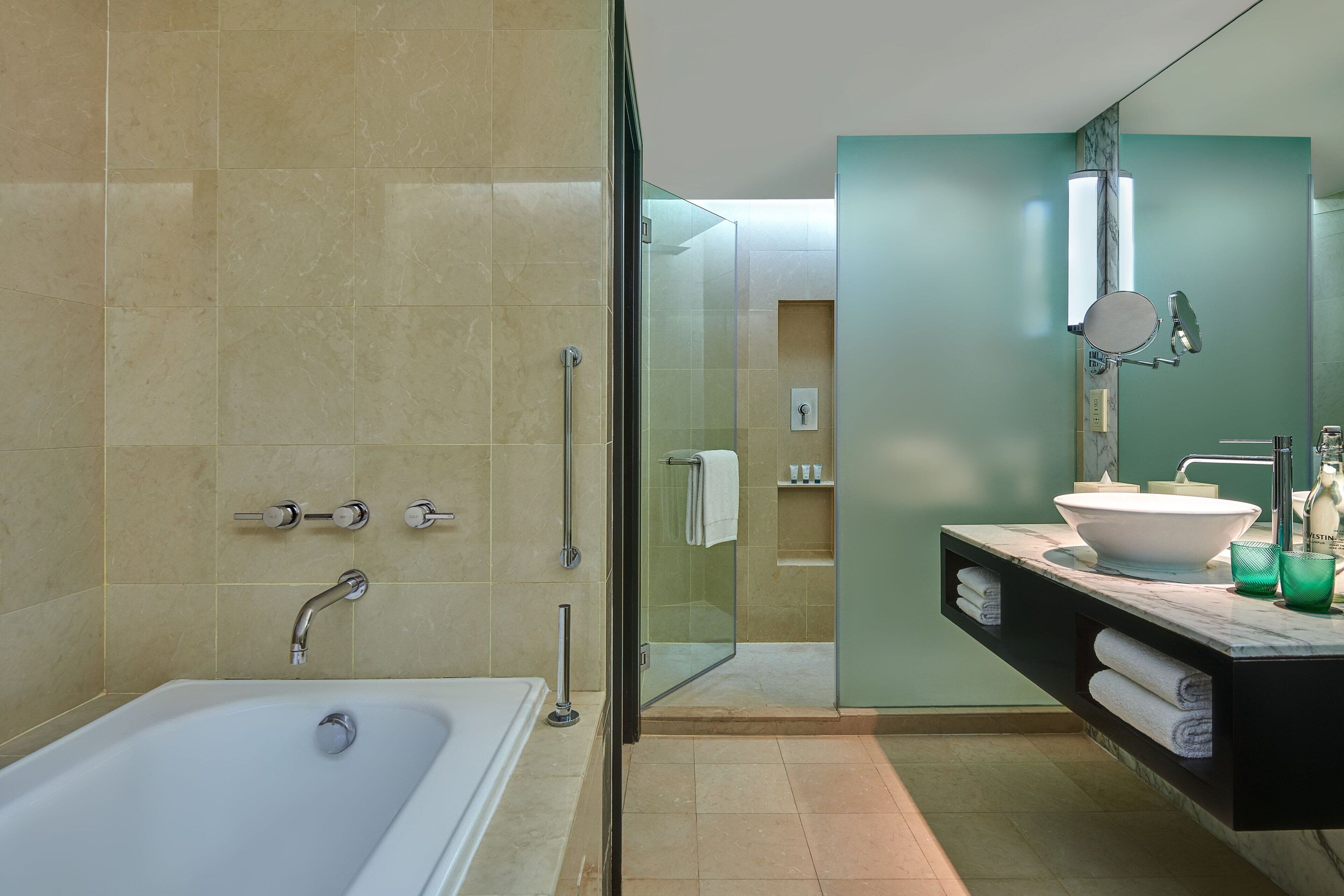A modern bathroom with a glass-enclosed shower, a white bathtub, and a vanity with a sink and mirror.