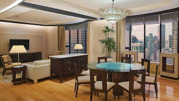 A modern living room with a glass dining table, wooden chairs, a sofa, and a TV.