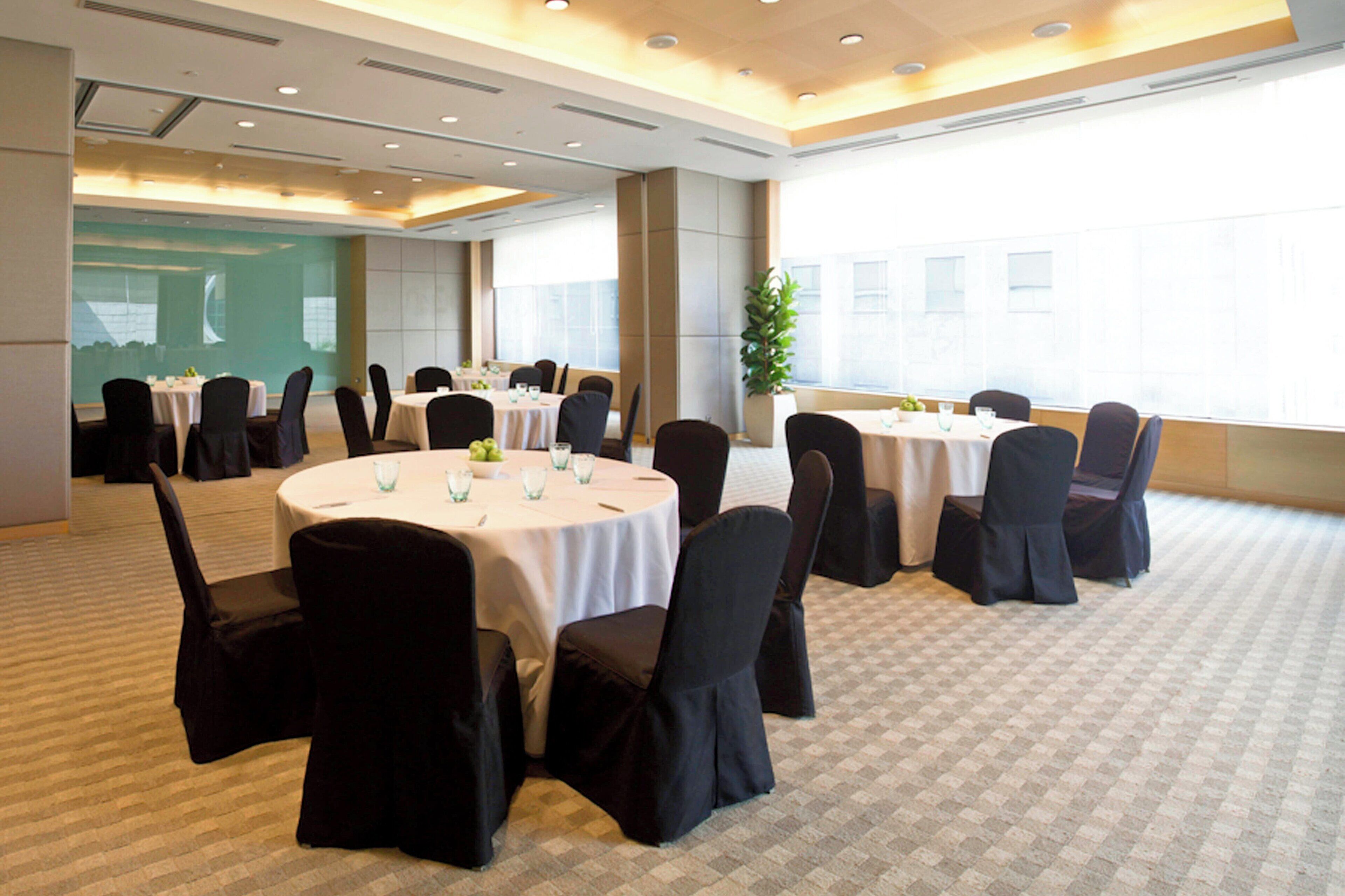 A conference room with round tables, black chairs, and a large window.