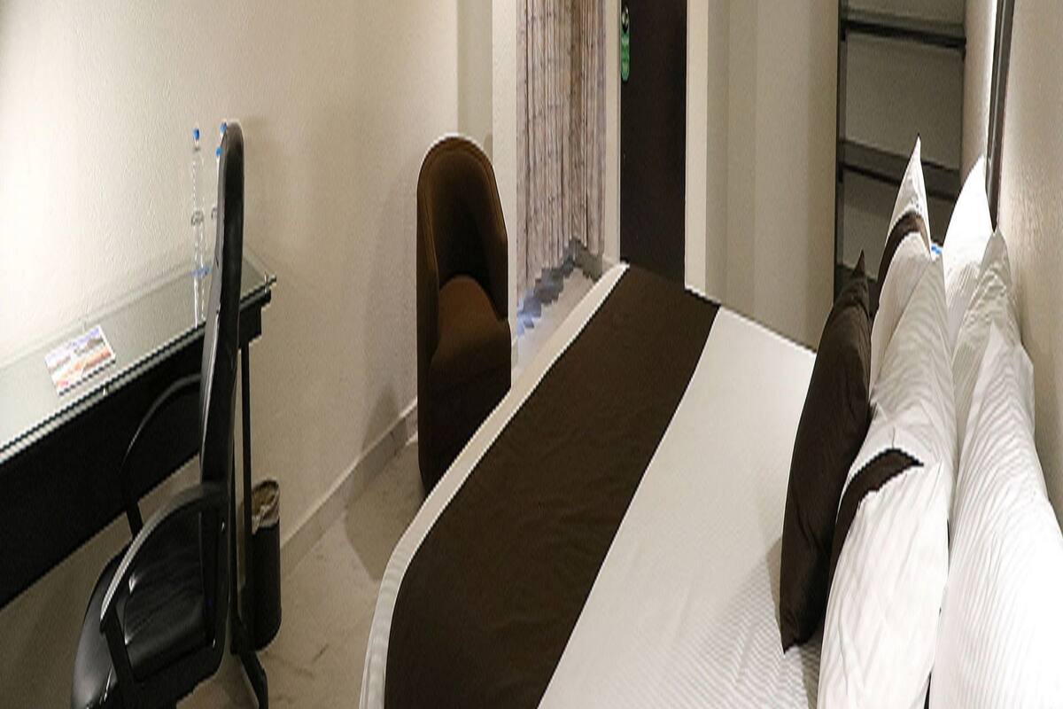 A hotel room with a bed, a desk, a chair, and a wardrobe.
