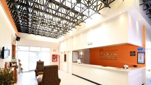 A reception area with a reception desk, patterned chairs, and a ceiling with exposed beams. - Misión Express Aguascalientes Zona Norte (Jesús María)