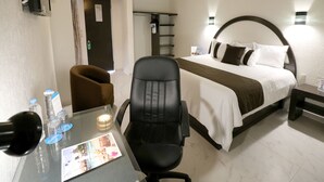 A hotel room with a bed, a desk with a chair, a lamp, and a water bottle. - Misión Express Aguascalientes Zona Norte (Jesús María)