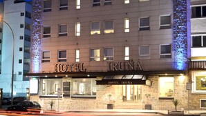 A multi-story hotel with illuminated signage, a stone facade, and a well-lit entrance. - Hotel Iruña (Mar del Plata)